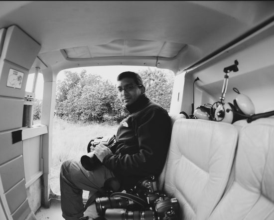 Trevor Peterson sitting in a bush plane doorway with his cameras and long lenses