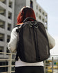A woman with red hair wearing a black Kiboko 2.0 16L+, seen from behind in the city