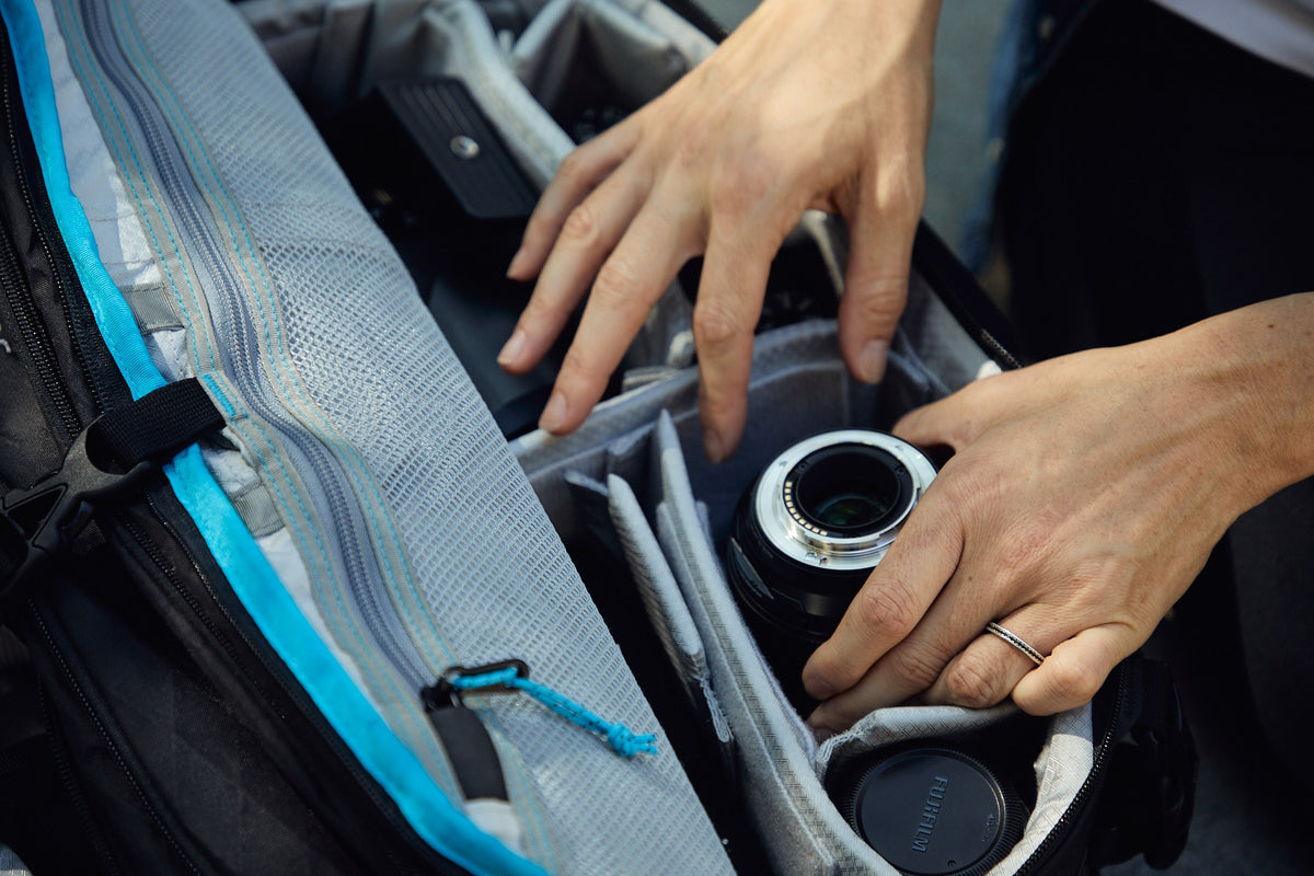 Hands lifting a lens out of the padded dividers of a Kiboko 2.0 22L+