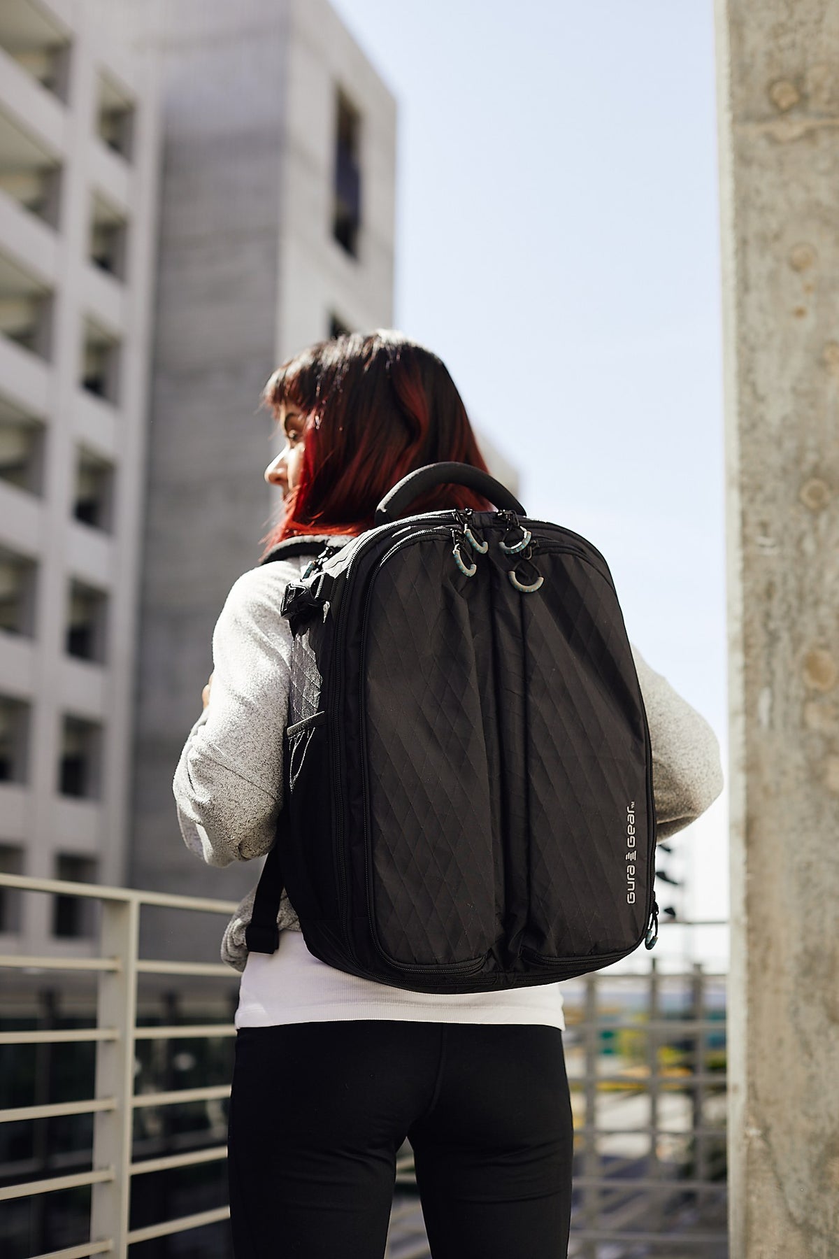 A woman wearing a black Kiboko 2.0 22L+, seen from behind in the city