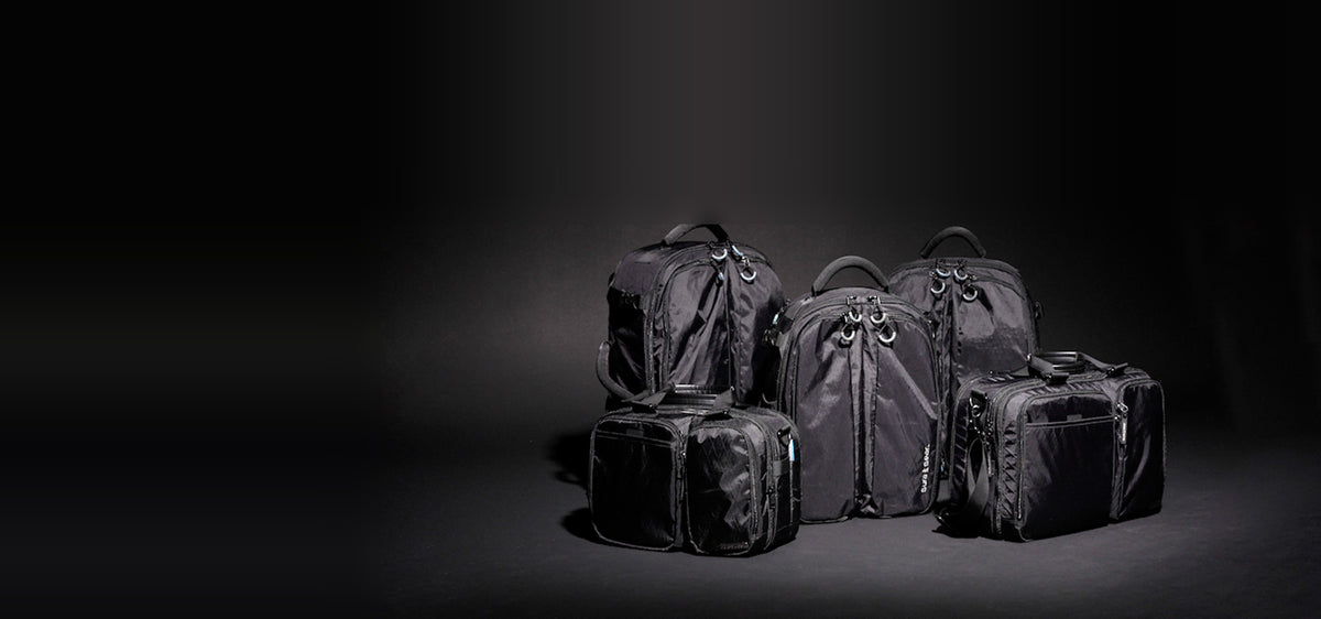 Gura Gear camera backpacks and bags grouped together on a dark studio floor